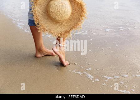 Nahaufnahme von Frauen barfuß Beine und Strawhat am Meer Stockfoto