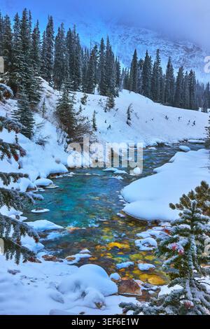 Der Winter River Fließt Durch Den Snowy Pine Forest Und Die Berge In Unberührter Wildnis Stockfoto