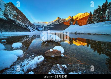 Winter Sonnenaufgang Reflektionen Snowy Lake Ice und Mountain Peaks Stockfoto