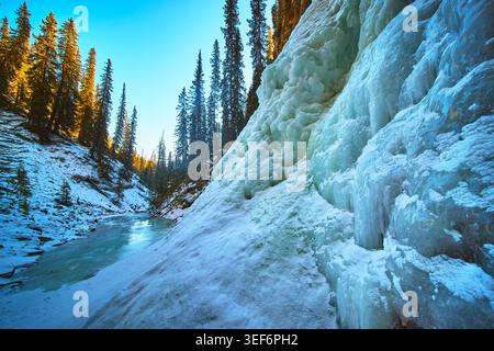 Gefrorener Wasserfall und verschneite Wälder entlang des Flusses im Winter Alberta Kanada Stockfoto