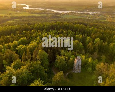Blick bei Sonnenuntergang auf den historischen Steinturm, umgeben von dichtem Wald und mäandernder Flusslandschaft. Bismarck Tower auf dem Gipfel von Zelena hora Stockfoto