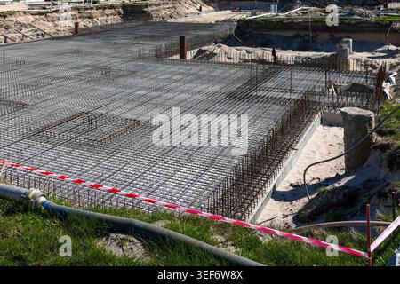 Weite Sicht auf das Stahlgitter-Fundament mit Bewehrungsgitter und Schalung, bereit für den Beton-Gießen auf einer Großbaustelle Stockfoto