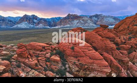 Red Rock Calico Formationen mit schneebedeckten Bergen bei Sunset Aerial Nevada Stockfoto