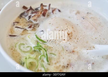 Cremige Tori Paitan Ramen mit schaumiger Hühnerbrühe, weichgekochtem Ei, zartem Hühnerchashu und frischen Nudeln, die appetitlich gefangen werden, helles Licht. Stockfoto