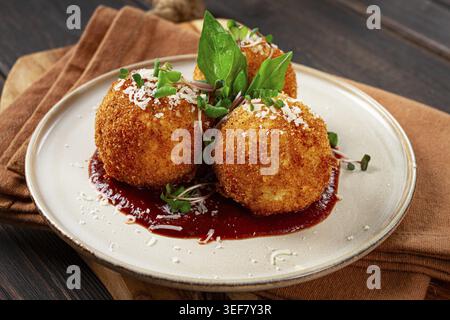 Knusprige Arancini-Vorspeise mit Parmesan und Mikrogrün, Teller, Tomatensauce, hausgemacht, keine Leute Stockfoto