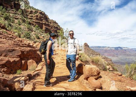 Zwei Wanderer in Rucksäcken lächeln, während sie auf dem staubigen, hellen Angelpfad stehen. Genießen Sie eine abenteuerliche Reise durch die Weiten. Robuste Kap Stockfoto