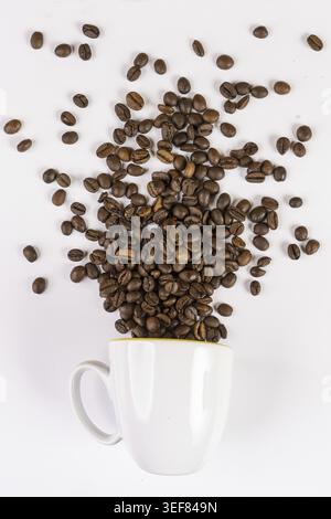 Kaffeebohnen kommen aus einer Tasse vor weißem Hintergrund Stockfoto
