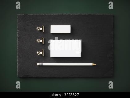 Foto von leeren Visitenkarten, Bleistift, Radiergummi und Clips auf Steintafel. Leere Vorlage für Schreibwaren. Flache Lagen Stockfoto