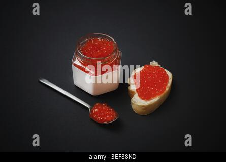 Köstlicher frischer roter Kaviar. Sandwich mit rotem Kaviar, Glas und Löffel Stockfoto