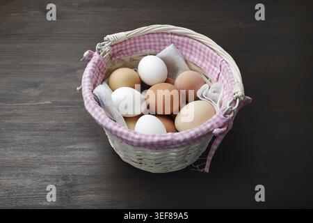 Eiern in Weidenkorb auf Holztisch Stockfoto