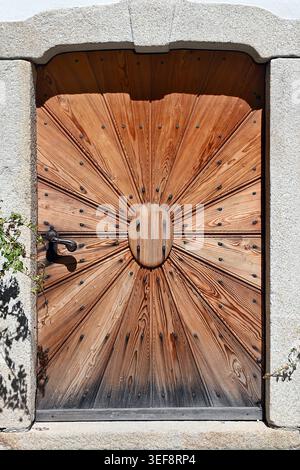 Sonnenschliff Holztür mit rustikalem Eisengriff im Steinrahmeneingang, Hallstatt, Österreich, im vertikalen Format Stockfoto