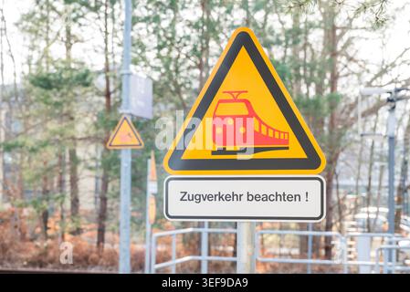 Ein dreieckiges gelbes Warnschild mit einem roten Zugsymbol und einem zusätzlichen Schild mit der Aufschrift „Acht auf Züge! " Auf den Zugverkehr achten). Stockfoto