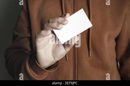 Die Hand des Mannes zeigt eine leere weiße Visitenkarte. Mann mit Visitenkarte Stockfoto