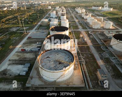 Aus der Vogelperspektive großer industrieller Lagertanks und Raffinerieinfrastruktur umgeben von grünen Feldern in Augusta, Sizilien, Italien. Stockfoto
