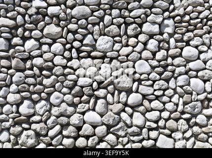 Wand aus weißen und grauen Meeressteinen und Kieselsteinen. Vollbild, Hintergrund und Textur. Stockfoto