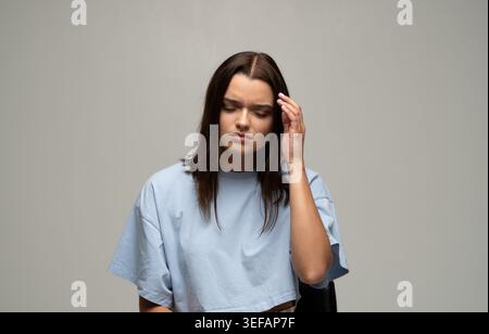 Junge Frau mit starken Kopfschmerzen oder Migräne, Müdigkeit, Stress, Schmerzen und gesundheitlichen Problemen Stockfoto