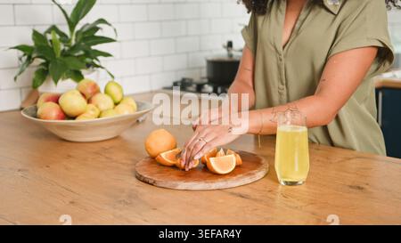 Frau Schneidet Orangen Auf Holzbrett In Der Hellen Küche, Die Frischen Saft Und Gesunden Snack Zubereitet Stockfoto