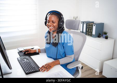 Afroamerikanische Krankenschwesterberatung am Computer mit Headset Stockfoto
