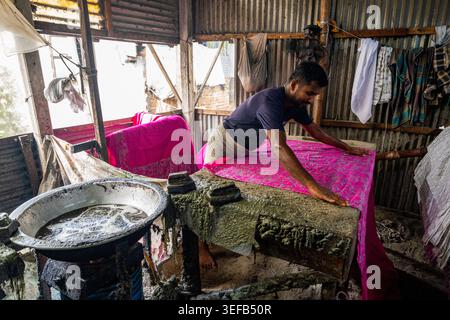 Der Mann färbt Batikkleidung in der Werkstatt im Dorf Araihazar, Bangladesch, während er Stoff für die Farbbehandlung vorbereitet Stockfoto