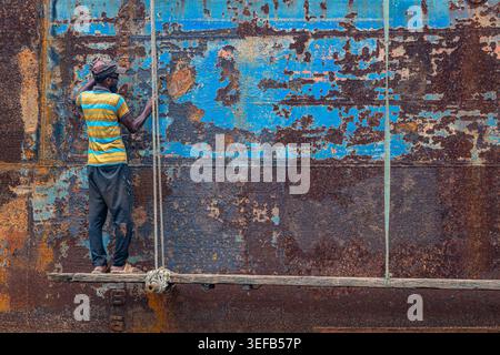 Männer reparieren ein Boot in einer Schiffswrack-Werft, während sie in Dhaka, Bangladesch, fleißig arbeiten und sich auf die anstehende Aufgabe konzentrieren Stockfoto