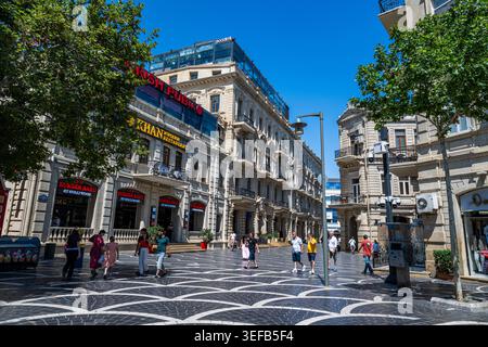 Die Leute laufen und genießen die Fußgängerzone in Baku unter klarem blauem Himmel Stockfoto