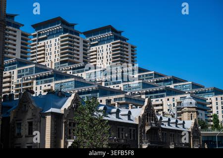 Blick auf moderne Hochhäuser in Baku mit älteren Gebäuden im Vordergrund während des Tages Stockfoto