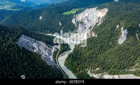 Aus der Vogelperspektive werden die Kurven der Rheinschlucht, umgeben von grünen Hügeln und steilen Klippen in der Schweiz bei Tageslicht, erfasst Stockfoto