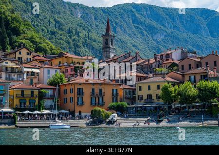 Varenna zeigt farbenfrohe Gebäude entlang der Küste des Comer Sees unter einem hellen Himmel mit Bergen im Hintergrund Stockfoto