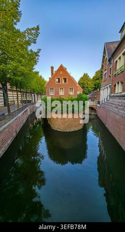 Ein kleiner Kanal fließt durch Bäume in der Nähe von Haus in Amiens, Frankreich an einem klaren Tag mit blauem Himmel Stockfoto