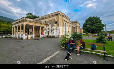 Besucher entspannen sich in der Nähe des Bahnhofs Gagra, während sich Wolken an einem kühlen Tag in Abchasien, Russland, sammeln Stockfoto