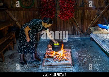 Die alte abchasische Frau bereitet Ajika über Feuer in der traditionellen Küche Russlands zu Stockfoto