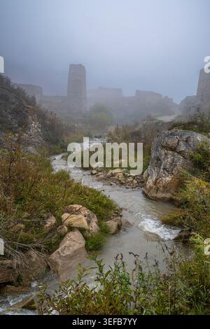 Verlassene Gebäude und Bach im Dorf Kamunta, umgeben von Nebel in Nordossetien, Russland Stockfoto