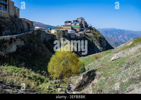 Das Bergdorf Tschoch in Dagestan zeigt Häuser auf einem Hügel mit einem Baum im Vordergrund unter einem klaren blauen Himmel Stockfoto