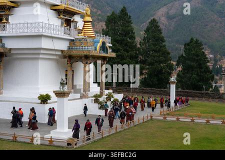 Besucher spazieren durch die National Memorial Chorten in Thimphu, Bhutan, und genießen dabei den Blick auf die Struktur und die Berge Stockfoto