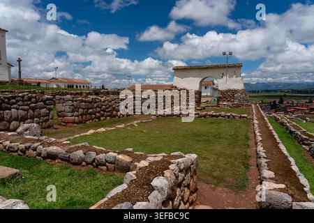 Erkunden Sie alte Steinmauern und grasbewachsene Gebiete an der archäologischen Stätte Chinchero in Peru an einem bewölkten Tag Stockfoto