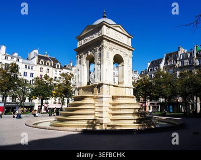 Fontaine des Innocents in Paris zeigt historische Architektur und geschäftiges Stadtleben unter hellblauem Himmel Stockfoto