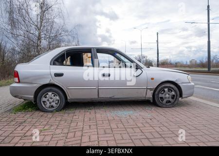 Prag, CZ -2023.03.04: Beschädigte silberne Limousine sitzt verlassen auf einem Bürgersteig mit zersplittertem Glas. Das Fahrzeug verfügt über einen defekten Seitenspiegel und einen MI Stockfoto