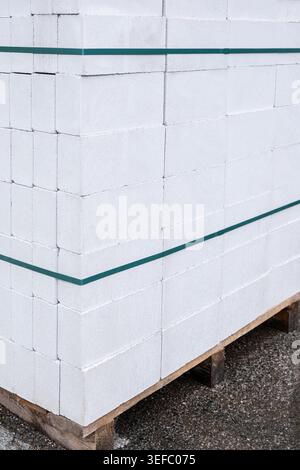 Der Stapel von Porenbetonblöcken wird mit einem grünen Band gesichert. Das Material wird in der Konstruktion für leichte und langlebige Strukturen verwendet. Stockfoto