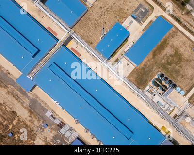 Von oben nach unten auf blaue Frachtkähne, die entlang des Flusses vertäut sind. Stockfoto