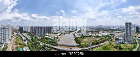 Weite Panoramasicht auf moderne Wohnkomplexe und Flussinfrastruktur in Ho Chi Minh City, Vietnam, unter hellem bewölktem Himmel. Stockfoto