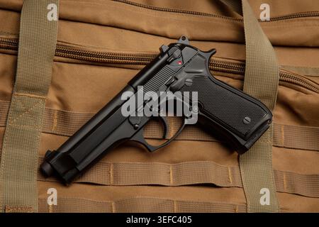 Schwarze halbautomatische Pistole, die auf einem braunen taktischen Textil-Hintergrund aufliegt Stockfoto