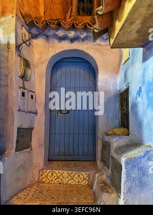 Eine lebendige blaue Tür und eine mit Kunsthandwerk dekorierte Gasse und die ikonischen Indigo-Wände der „Blauen Stadt“ – Chefchaouen, Marokko. August 2025 Stockfoto