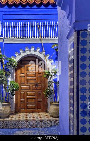 Eine lebendige blaue Tür und eine mit Kunsthandwerk dekorierte Gasse und die ikonischen Indigo-Wände der „Blauen Stadt“ – Chefchaouen, Marokko. August 2025 Stockfoto