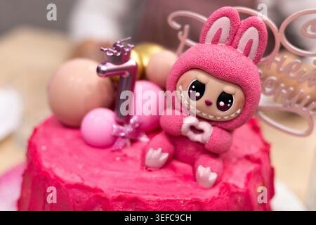 Niedliches rosafarbenes Spielzeughase auf Kuchen und Süßigkeiten auf einem festlichen Tisch, verspielte Feier, süße Dessertstimmung, Geburtstagsspaß, Ostern. Stockfoto