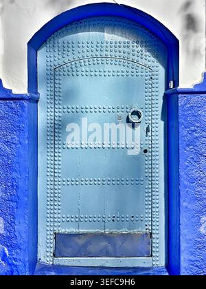 Eine lebendige blaue Tür und eine mit Kunsthandwerk dekorierte Gasse und die ikonischen Indigo-Wände der „Blauen Stadt“ – Chefchaouen, Marokko. August 2025 Stockfoto