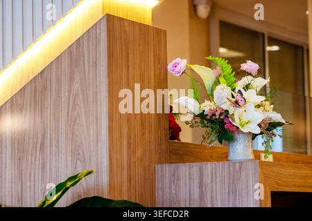 Dieses elegante Blumenarrangement zeigt einen farbenfrohen Blumenstrauß in einer stilvollen Vase, der auf einer modernen Holzoberfläche in einem gemütlichen Interio präsentiert wird Stockfoto