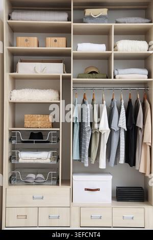 Kleiderschrank mit verschiedenen stylischen Kleidungsstücken, Accessoires und Wohnaccessoires im Innenbereich Stockfoto
