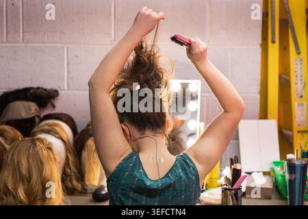 Ein Mädchen im Theater frisst sich hinter der Bühne vor einem Spiegel die Haare Stockfoto
