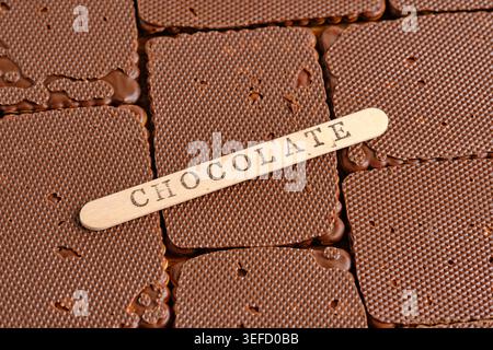 Abgewinkelte Schokoladenkekse mit hölzernem Etikett mit Wort „SCHOKOLADE“ auf der Oberseite Stockfoto