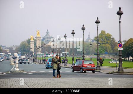 Romantisches Paar küsst sich auf der Pont Alexandre III in Paris, Frankreich, im Oktober 2015, mit kunstvollen goldenen Skulpturen, historischer Architektur und bewölktem Himmel Stockfoto